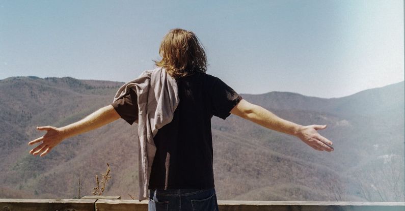 Expansion - Back View of a Man Stretching Hands in a Mountain Landscape