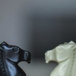 Puzzle Board Games - Closeup of black and white figures of knight standing in front of each other on chessboard square