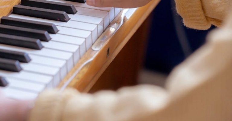 Solo Play - High angle of crop anonymous female musician practicing music on piano at daytime